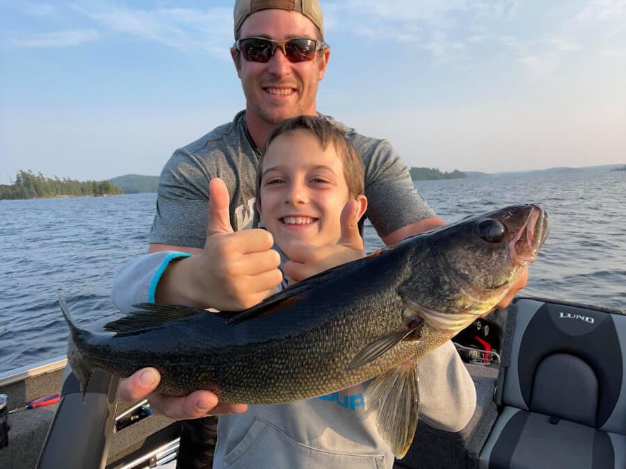 Kid and Dad holding fish in boat 