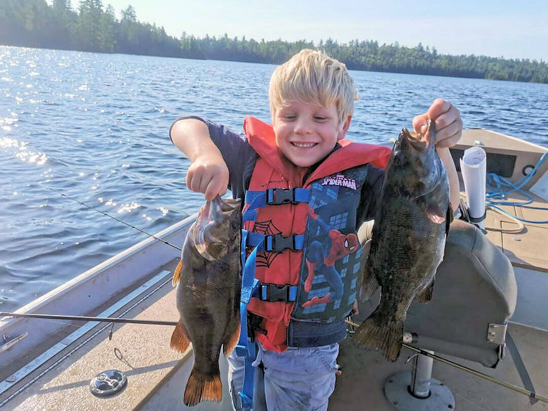 Kid holding two smallmouth bass